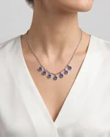 Collar de acero con cadena de eslabones finos y dijes circulares colgantes con circonias azules engastadas.