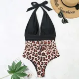 Malla entera combinada con parte superior lisa de color negro, escote halter cruzado y corpiño triangular con copas desmontables. Parte inferior de tiro alto con estampado animal print tipo leopardo.