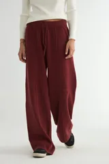 Pantalón tejido de corte recto y tiro alto, color beige, con cintura elástica ajustable mediante cordón y costura central vertical en cada pierna.