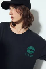 Remerón negro de manga corta, calce amplio y efecto gastado. Presenta una estampa gráfica de inspiración retro en el frente y la espalda.