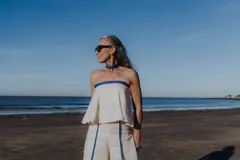 Top strapless blanco de corte suelto y acampanado, con detalle de ribete con brillos azules en el escote.