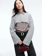 Sweater de punto en color gris, con diseño crop de mangas largas y cuello bote. Presenta una textura acanalada y un corte moderno que permite superposiciones.