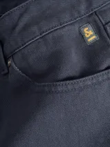 Pantalón de vestir azul marino, de corte recto, con bolsillos laterales y traseros. Se ajusta a la cintura con cinturón de cuero marrón.