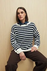 Sweater de punto con diseño de rayas horizontales en azul marino y blanco, con detalle de calados y cuello redondo. Presenta mangas largas con puños acanalados y un corte relajado.