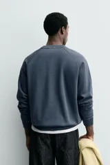 Sudadera regular fit color azul, de cuello redondo, manga larga ranglán y efecto lavado con acabados en rib.