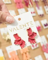 Aros tipo pendiente de diseño floral abstracto con pétalos esmaltados en color fucsia y bordes dorados.