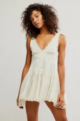 Mini vestido slip de tela satinada color blanco, con escote en V pronunciado, detalles de encaje y diseño en capas de corte babydoll.