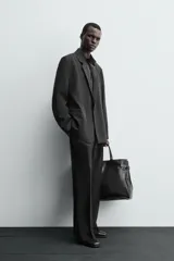 Blazer negra de corte relajado confeccionada en tejido con mezcla de lyocell. Tiene cuello con solapas de muesca, manga larga con puños abotonados, bolsillos de doble vivo en la cadera, bolsillo interior y cierre frontal cruzado con botones.