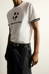 Camiseta de corte relajado confeccionada en piqué de algodón color crudo. Presenta cuello redondo, mangas cortas con ribetes a contraste y estampado frontal con el logo de Italia 90 FIFA World Cup.