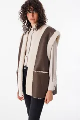 Chaleco reversible de cuero napalan color marrón con interior de corderito color crema. Tiene silueta holgada, terminaciones a la vista y bolsillos laterales.