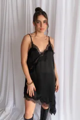 Vestido corto de satén negro, con tirantes finos, escote en V y detalles de encaje en el escote, el lateral y el dobladillo asimétrico.