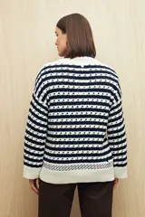 Sweater de punto con diseño de rayas horizontales en azul marino y blanco, con detalle de calados y cuello redondo. Presenta mangas largas con puños acanalados y un corte relajado.