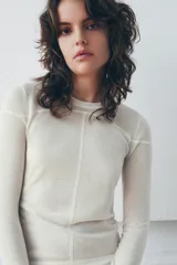 Jersey de punto fino con diseño color block en tonos rojo, bordó y blanco. Presenta cuello redondo y manga larga.