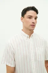 Camisa de manga corta confeccionada en lino y algodón, con fit regular y logo bordado. Color beige con rayas verticales blancas.