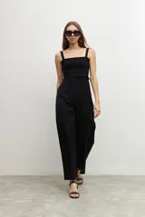 Mono negro de corte palazzo, con breteles finos y escote recto con detalle de smock.