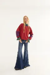 Remera de manga larga con corte boxy, confeccionada en algodón. Presenta un diseño de rayas horizontales en tonos azul y fucsia, con detalles de rayas verticales en los codos, tajos laterales y logo bordado en el pecho.