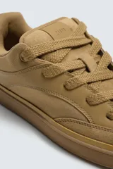 Zapatillas acordonadas color ocre, con suela de goma marrón con volumen.