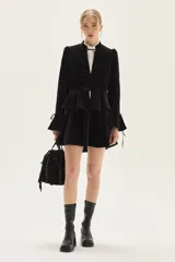 Cartera tipo bandolera de cuero gamuzado color marrón, con diseño de flecos laterales y detalle de tachas metálicas. Cuenta con cierre de cordón ajustable con borlas y correa regulable.