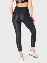 Calza deportiva de tiro alto con cintura en forma de V, confeccionada en tela brillante con acabado satinado. Presenta un ajuste ceñido tipo segunda piel y cuenta con silicona en el interior de la cintura para mayor sujeción.