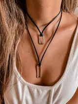 Collar doble con cadena de cuero sintético negro y dije rectangular plateado.