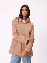 Campera rompevientos color tostado con capucha ajustable mediante cordones, cierre frontal completo y bolsillos laterales. Presenta el logo de la marca bordado en el pecho y puños con ajuste de botón.