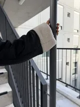 Campera tipo gamulán de cuero sintético negro con interior y detalles de corderito blanco. Presenta cierre frontal, bolsillos laterales y diseño holgado.