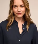 Camisa de manga larga color verde lima, con cuello camisero y botonadura frontal. Presenta un dobladillo trasero más largo que el delantero.