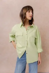 Camisa de denim liviano color verde claro, con corte oversize, cuello camisero, mangas largas con puños, cierre frontal con botones y dos bolsillos delanteros con tapa.