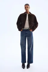 Campera corta de color marrón oscuro con cuello camisero, cierre frontal mediante botones y dos bolsillos delanteros con solapa. Presenta un diseño forrado y corte recto.