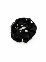 Gomita para el pelo tipo scrunchie de tela negra con estampado de lunares blancos.