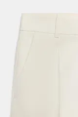 Pantalón cropped de tiro medio con cintura con trabillas, bolsillos laterales y detalle de nervio frontal. Cierre con cremallera, botón y ganchos metálicos.