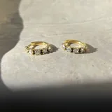 Par de aros tipo argolla de plata 925 con acabado en oro de 18k, decorados con circonias blancas y negras.
