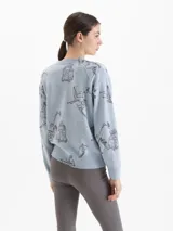 Sweater de lana color celeste con silueta holgada, cuello redondo y mangas largas. Presenta un estampado integral de paisajes de montaña y esquí, con la frase 'Chic sur les pistes' bordada en relieve en color bordó.