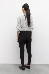 Pantalón chupín elastizado negro con cierres laterales y costuras a lo largo de ambas piernas.