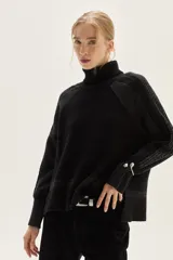 Polera de cuello alto tejida en lana, con diseño de manga raglán y calce holgado. Presenta detalles en contraste y sutiles destellos de lurex, con cambios de textura en el tejido y bordado artesanal en la espalda.