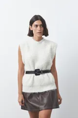 Chaleco de punto con textura afelpada, cuello redondo y hombros marcados. Presenta una silueta relajada y un diseño sin mangas.