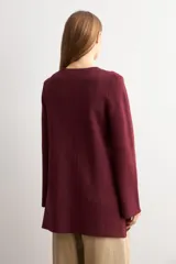 Sacón tejido color bordó, de corte recto y largo medio, con cuello redondo, cierre frontal con alamares y botones dorados, y bolsillos aplicados al frente.