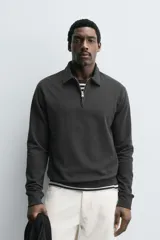 Polo de manga larga color gris oscuro, con diseño de textura estructurada, cuello solapa y cierre frontal de cremallera corta. Cuenta con puños y cintura de rib elástico.