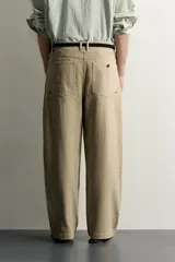 Pantalón relaxed fit de color beige, confeccionado en tejido con mezcla de algodón y lino, con diseño de cinco bolsillos, efecto lavado y cierre frontal con cremallera y botón.