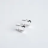 Aros tipo argolla pequeña de plata 925, con diseño cuadrado y detalle de una circonia engastada en la parte superior.