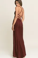 Vestido largo de fiesta confeccionado en tela lurex color bordó. Presenta un escote recto con breteles finos, corte ajustado al cuerpo y una abertura lateral profunda en la falda.