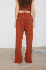 Pantalón de corte recto confeccionado en tela sastrera color ladrillo, con tajo lateral en la botamanga y bolsillos laterales.
