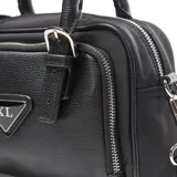 Cartera negra de simil cuero con doble asa corta y correa larga extraíble. Tiene cierre superior, bolsillo interno con cierre, herrajes plateados y logo XL en el frente.