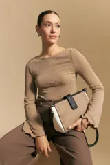 Top negro de manga larga acampanada con escote pronunciado en la espalda que se ajusta con lazos. La tela presenta una textura sutil con brillo, similar a un animal print discreto.