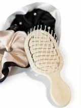 Kit de accesorios para el cabello que incluye un neceser transparente con borde blanco, dos scrunchies (uno negro con perlas y uno beige), dos clips livianos, una pinza dorada, un peine protector para desenredar y un peine para abrir ondas y rulos.