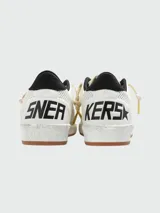 Championes Golden Goose modelo Ball Star HF, color blanco con detalles en negro, confeccionados en cuero perforado, con cordones color crema, estrella distintiva en el lateral y suela con efecto envejecido.