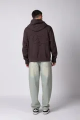 Buzo canguro de corte oversize en color gris con efecto lavado desgastado. Presenta diseño con recortes horizontales, capucha amplia y puños acanalados con etiqueta de marca en la manga.