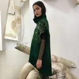 Poncho verde esmeralda de lana merino afieltrada con cuello alto y estampado dorado con diseño abstracto.