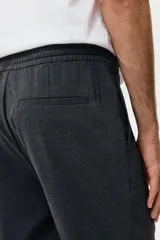 Pantalón tipo jogger de vestir con pliegues frontales y traseros, cintura elástica con cordón de ajuste, bolsillos laterales al bies y bolsillos traseros insertados. Presenta un corte slim fit entallado.