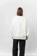 Buzo oversize de cuello redondo, confeccionado en algodón suave con interior frizado. Presenta un diseño de líneas simples, corte relajado y mangas largas con puños ajustados.